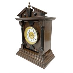 Fattorini of Bradford - oak cased early 20th century mantle clock with alarm, rectangular case with a broken pediment, turned finial and matching carved pilasters to the front, on a broad stepped plinth with a flat base, circular dial with an ivorine chapter within a decorative gilt bezel, Arabic numerals , spade hands and alarm setting disc to the centre, two train spring driven movement striking a coiled gong and bell. With key and pendulum. 