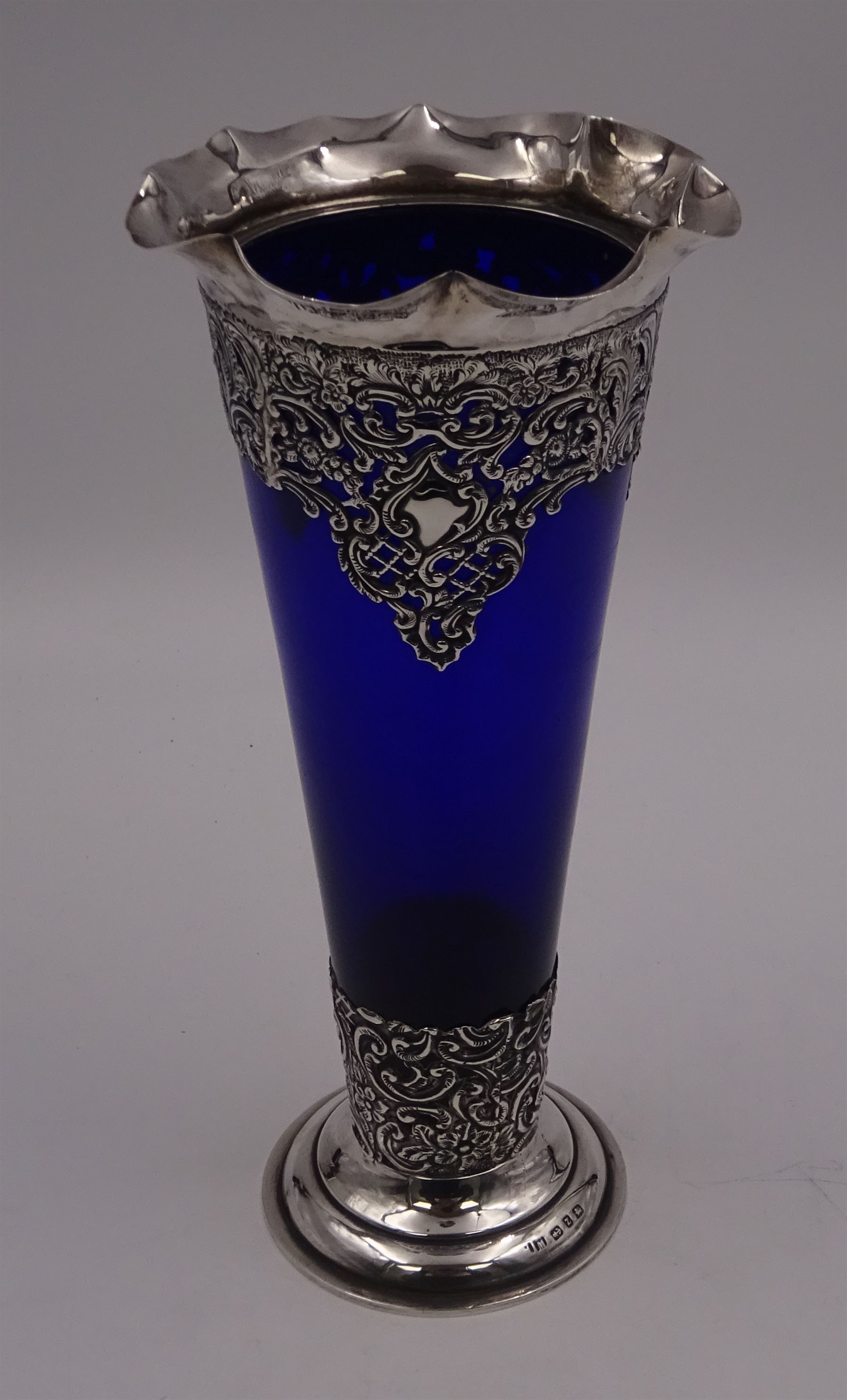 Victorian silver mounted blue glass trumpet vase, the silver mounts with pierced and embossed floral, C scroll and lattice decoration, with frilled rim, upon stepped circular foot, hallmarked Henry Matthews, Birmingham 1899