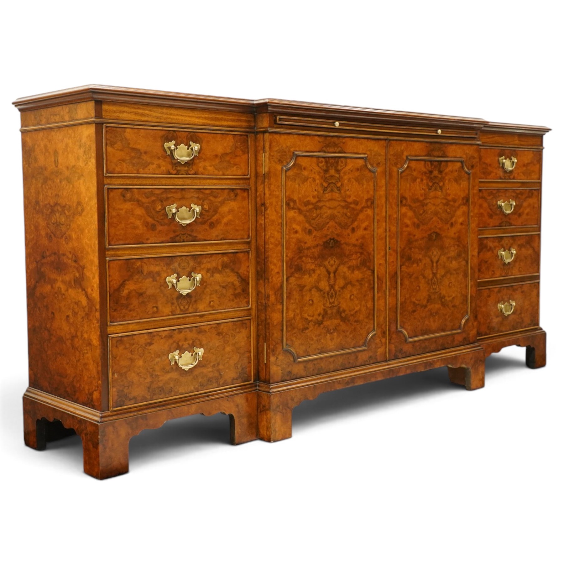 Georgian design figured and burr walnut breakfront sideboard, shaped rectangular top inlaid with crossbanding and stringing, fitted with central brushing slide over cupboard enclosing single adjustable shelf, flanked four graduating cock-beaded drawers to each side, raised on bracket feet