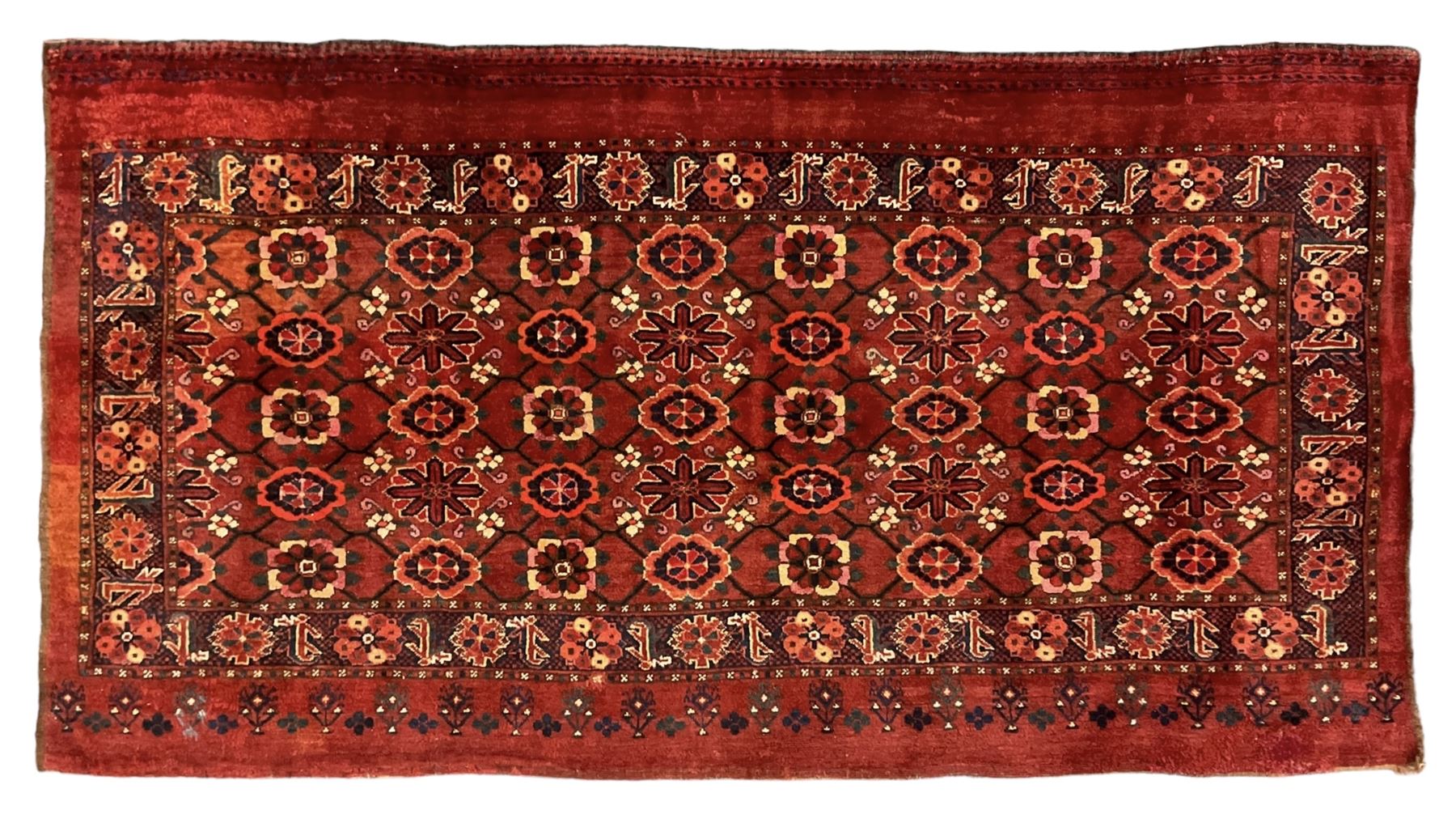 Persian red ground rug, the field decorated with lattice pattern and flowerhead, repeating border decorated with flower heads and leaf motifs