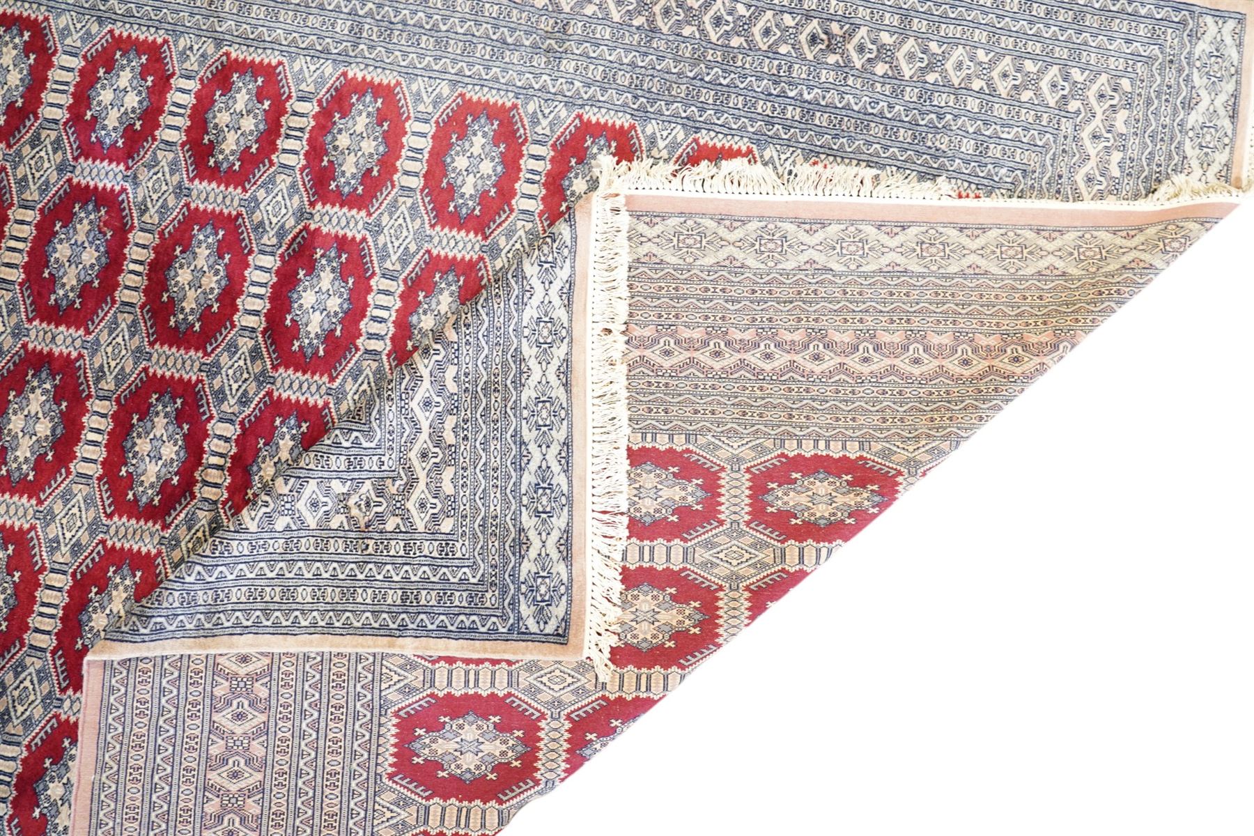 Jaldar Bokhara crimson and pale ground carpet, the field decorated with five rows of Gul motifs, within intricate multi-band border decorated with repeating geometric designs 