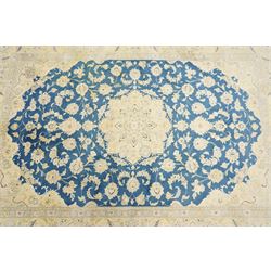 Central Persian Nain hand-knotted rug, sky blue field, with a central cusped medallion in ivory and soft camel tones, issuing an elegant arrangement of scrolling arabesques, palmettes and flowering vines, conforming ivory spandrels, principal pale border decorated with floral sprays and palmettes, flanked by narrow ground borders, with cotton fringe ends  