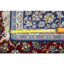 Fine Central Persian Isfahan hand-knotted rug, madder red field with central finely drawn foliate medallion issuing an intricate all-over scrolling vine design with palmettes and arabesques, enclosed by multiple conforming borders in navy ground, signed Isfahan in cartouche, silk fringe ends 