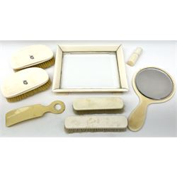 Early 20th century ivory dressing table set, comprising small footed tray with glass centre, handheld mirror, two hair brushes, two clothes brushes, cylindrical toothpick/pin case and shoe horn. 