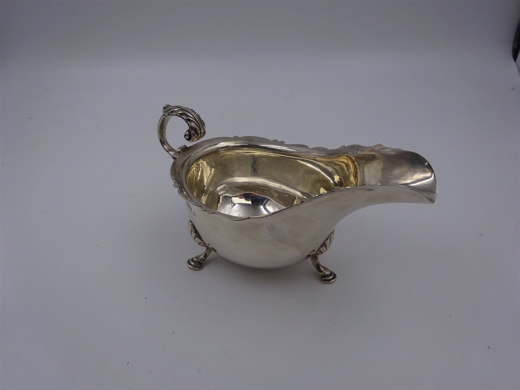 Early 20th century silver sauce boat, of typical form with shaped rim and acanthus capped flying C scroll handle, upon three palmette mounted hoof feet, hallmarked Thomas Edward Atkins, Birmingham 1915, including handle H8.5cm