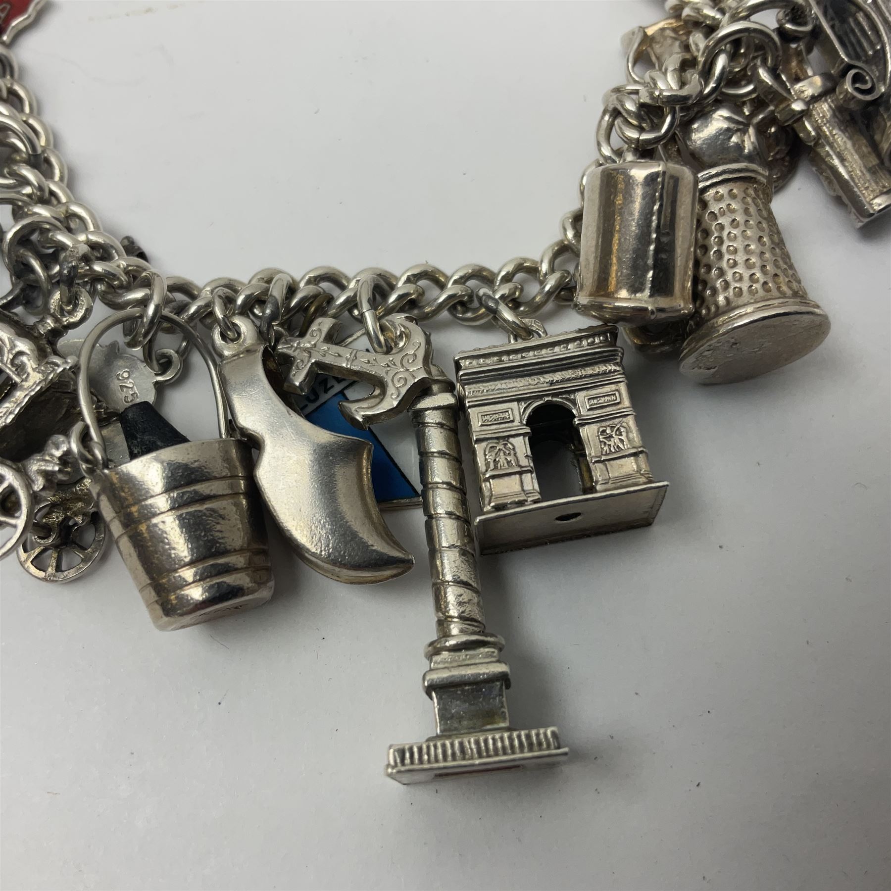 Silver charm bracelet, with twenty eight charms, including typewriter, rocking chair, carriage, cauldron, etc