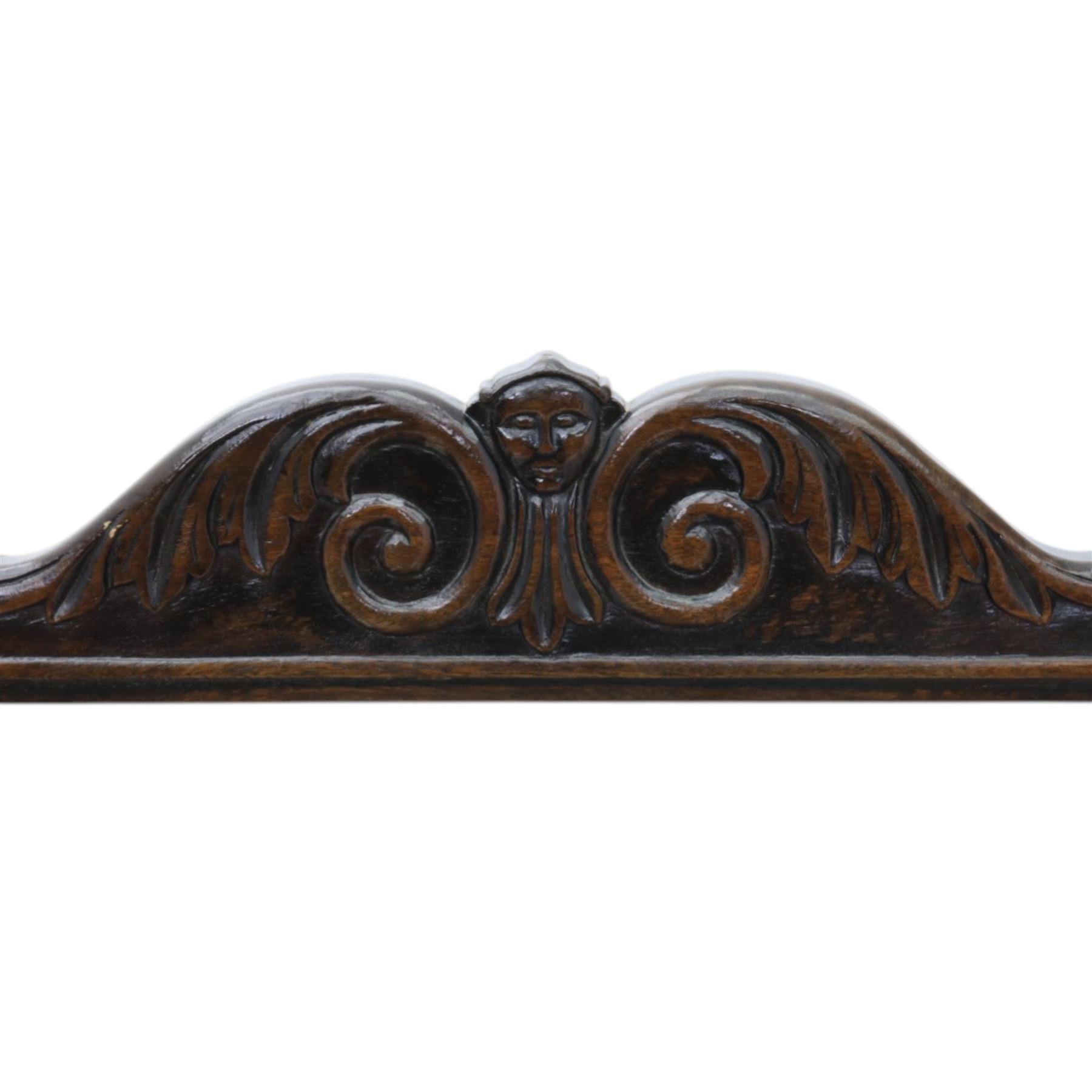 Late 20th century stained beech Savonarola chair, the carved crest rail and open arms above an upholstered leather seat, raised on an X framed base with carved foliate and mask decoration, joined by turned stretcher and ending in castors