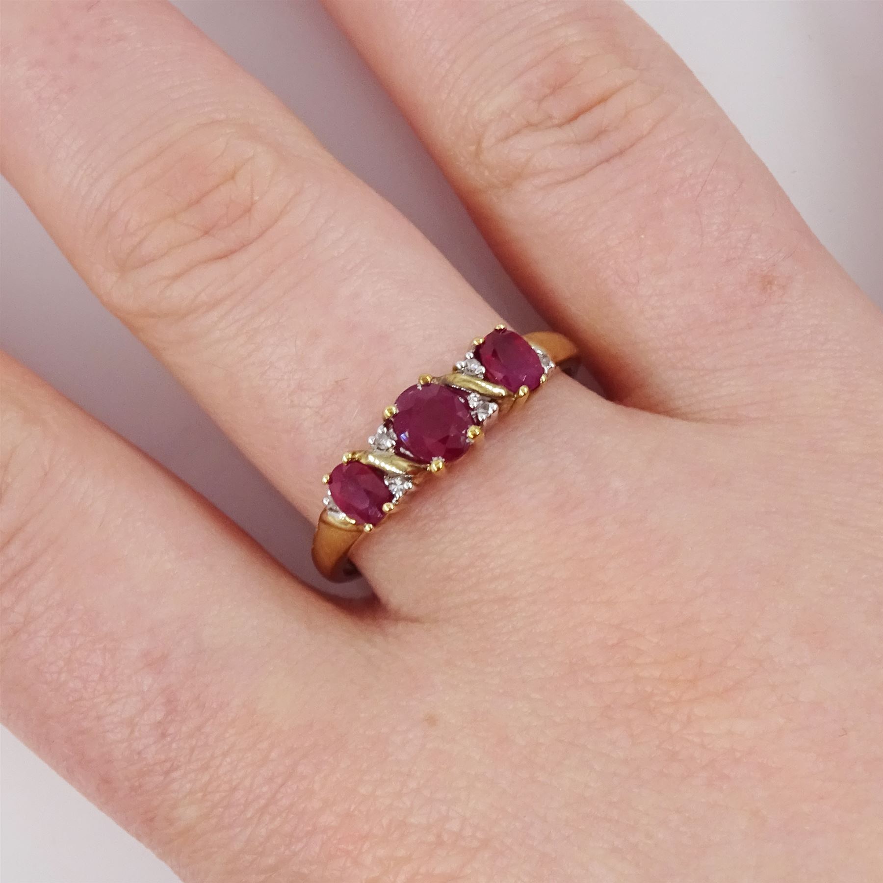 9ct gold ruby and diamond ring, three oval cut rubies spaced by six accent diamonds, stamped 9k