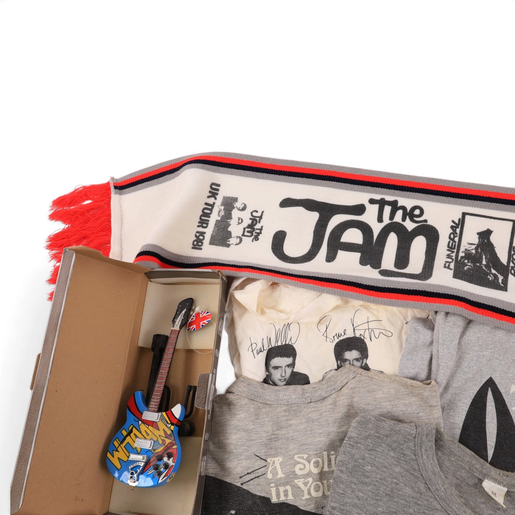 Five 1980s The Jam/Paul Weller/The Style Council tour/band t-shirts, including Cafe Bleu, The Paul Weller Movement, Dig The New Breed, A Solid Bond in Your Heart and Beat Surrender Tour 1982, together with a 1981 The Jam tour scarf and a Baby Axe Company miniature model of Paul Weller's Rickenbacker guitar