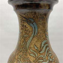 John Egerton (c1945-): studio pottery stoneware vase decorated with cranes in a riverscape upon a mottled brown ground, signed beneath H60cm