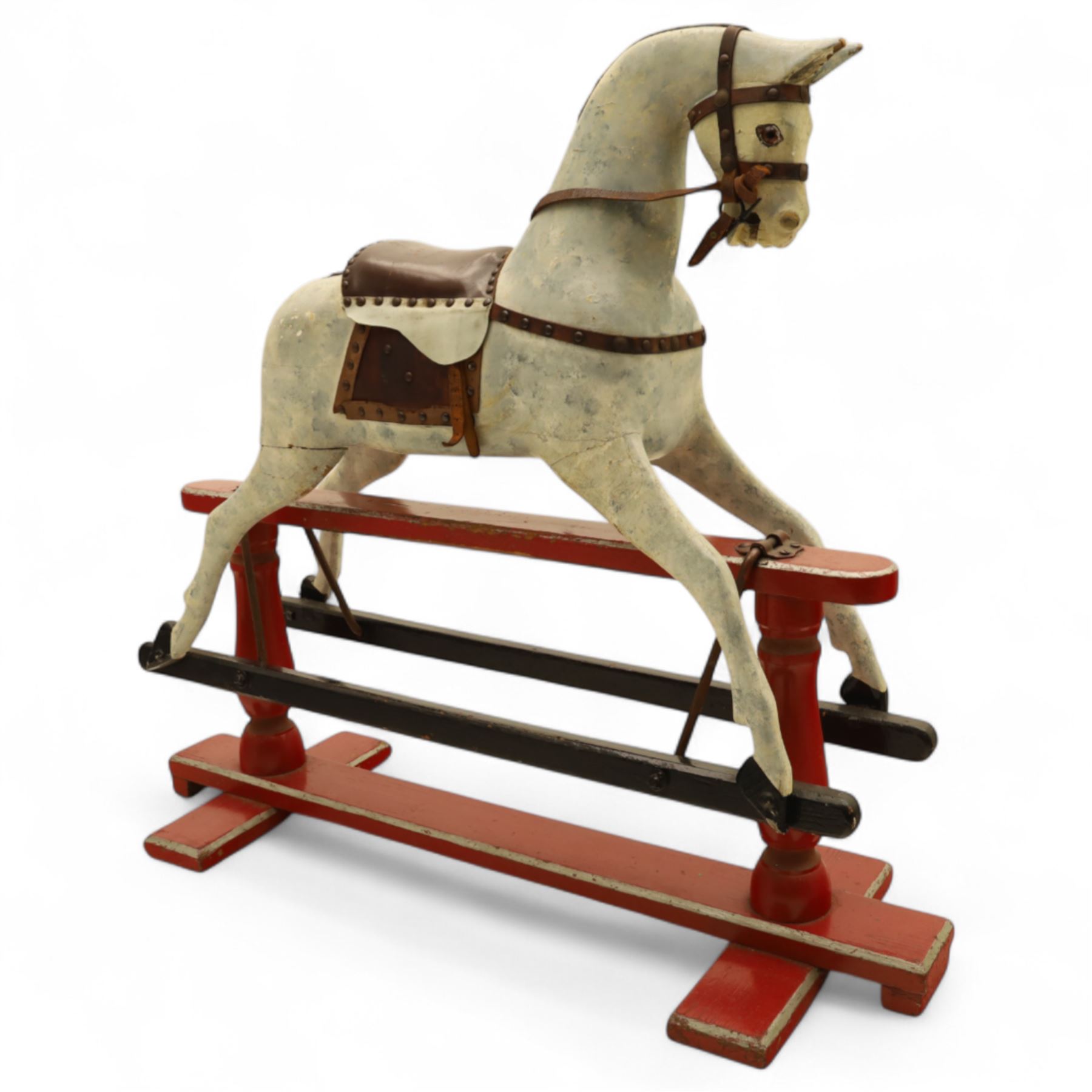 20th century carved and painted rocking horse, with original dappled paint finish, studded leather saddle and reins, on later red and black swing frame