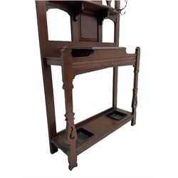 Late 19th century walnut hallstand, raised central bevelled mirror over shelf and hinged compartment, fitted with umbrella and stick stands with metal drip trays, upright pierced silhouette type supports