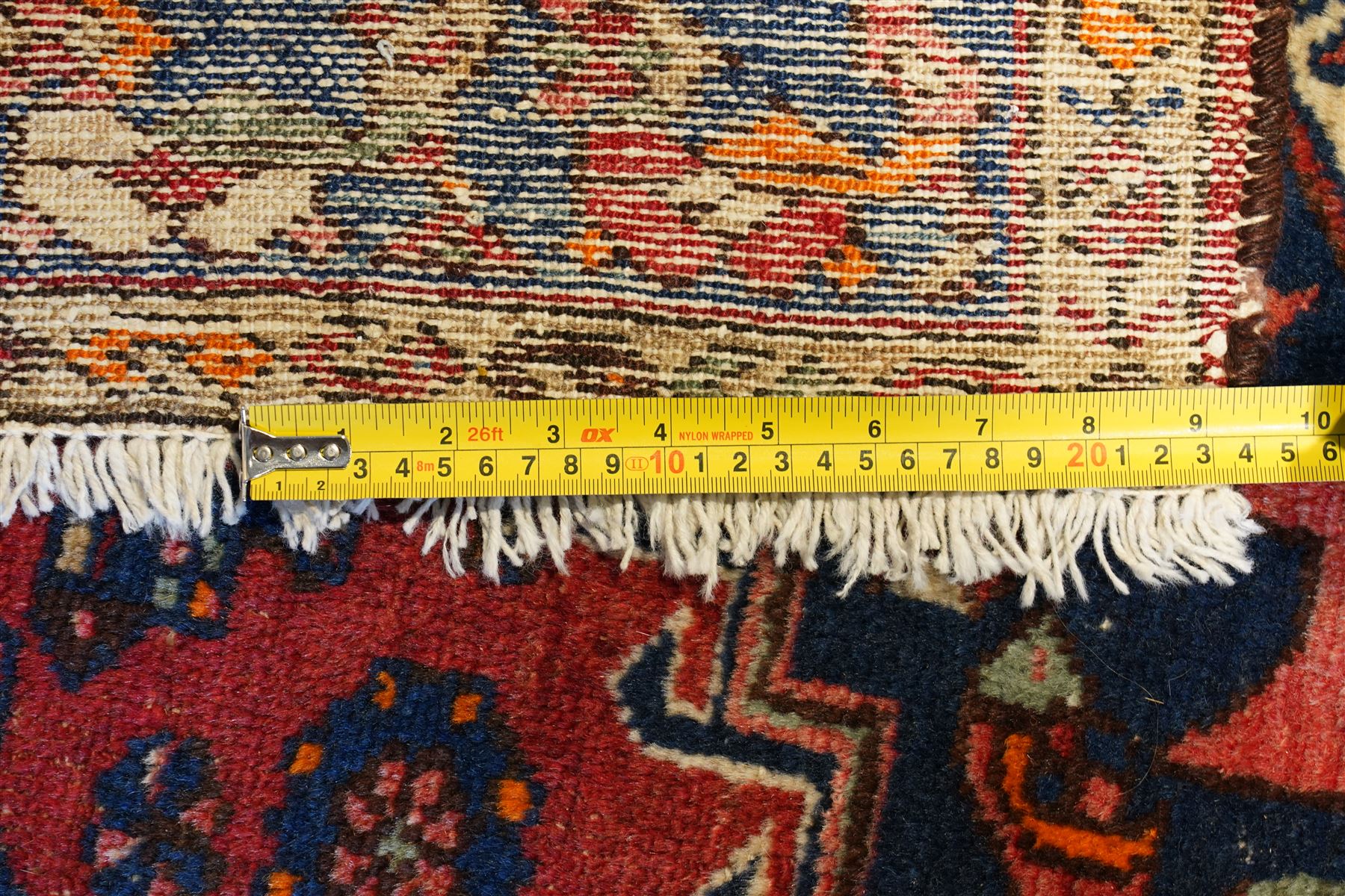 Persian Heriz crimson ground carpet, the central navy geometric medallion on a red crimson ground field, surrounded by further geometric stylised motifs and foliate designs, enclosed by multiple guard-lines  