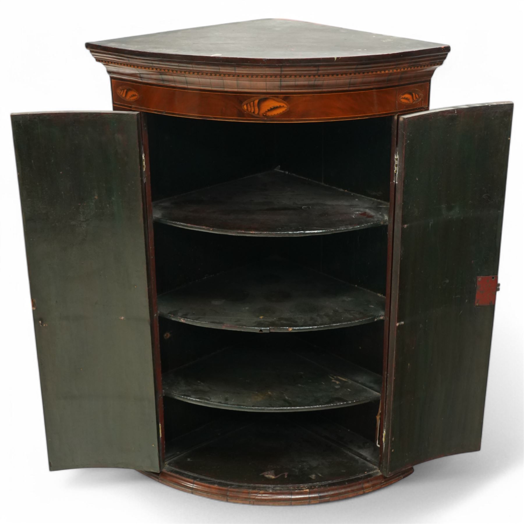 George III inlaid mahogany cylinder corner cupboard, projecting moulded cornice over figured frieze inlaid with shell motifs, two doors with checkered stringing enclosing three shelves, circa 1800