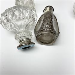 Silver collared and lidded glass perfume bottles and atomisers, to include a Hong Kong bottle covered with oriental sterling silver design with three concave oval windows, cylindrical glass scent bottle with foliate silver screw thread cap stamped Birmingham 1911 and six other silver capped examples, along with seven white metal mounted glass scent bottles including coloured and faceted examples (15)