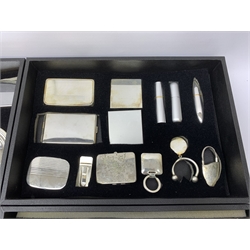  A large carry case opening to reveal five fitted trays containing a selection of assorted items, including various cufflinks, key rings, atomisers, card holders, photo frame, corkscrew, bottle opening, a number of desk clocks, calculators, pen holder, etc.   
