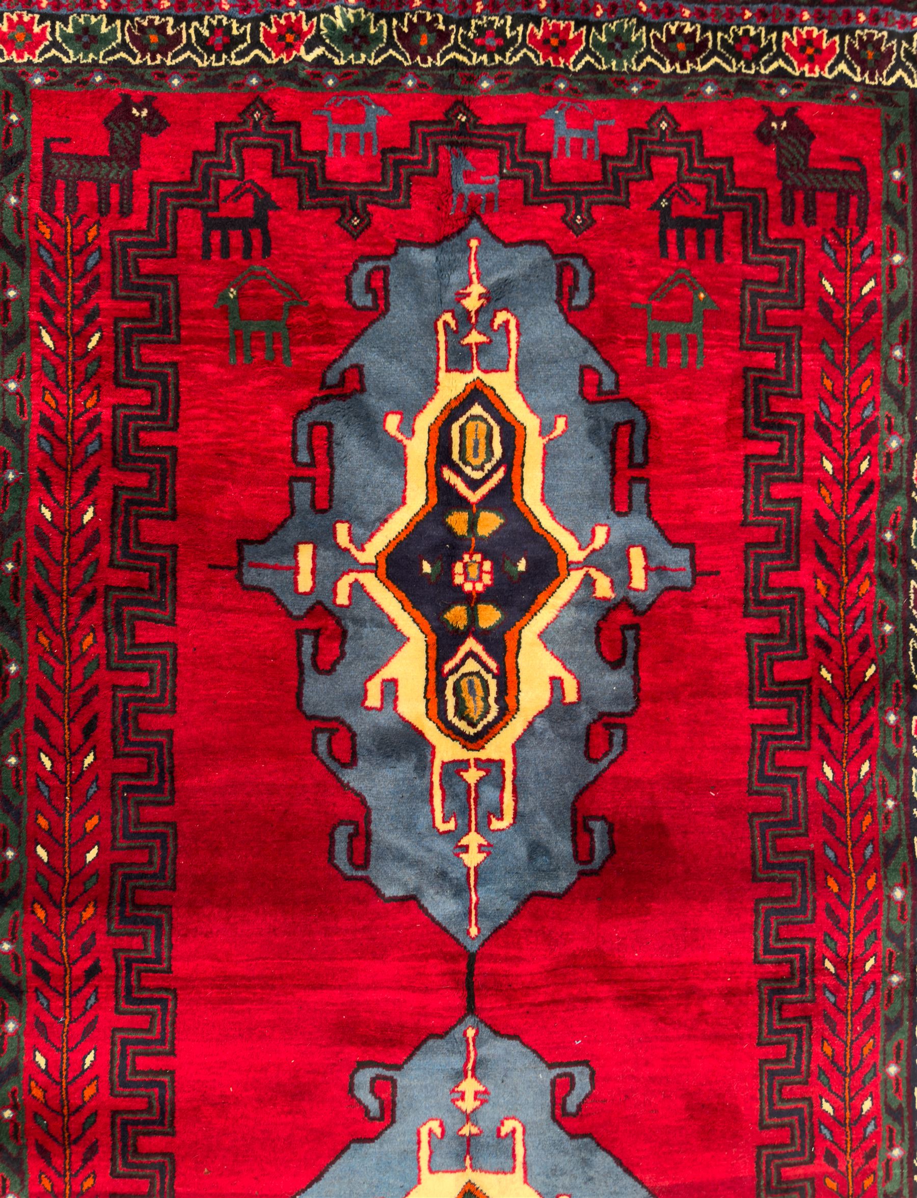 Northwestern Persian Cirjan hand-knotted carpet, madder red field with three linked stepped lozenge medallions in blue, ivory and green, flanked by angular motifs within a dark green border of serrated leaves and rosettes 