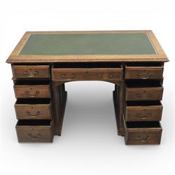 Victorian oak pedestal desk, the rectangular top with inset green leather writing panel and decorative gilt border, over a central frieze drawer flanked by two short drawers, twin pedestals each fitted with four drawers with brass handles, arched kneehole opening, standing on moulded plinth bases