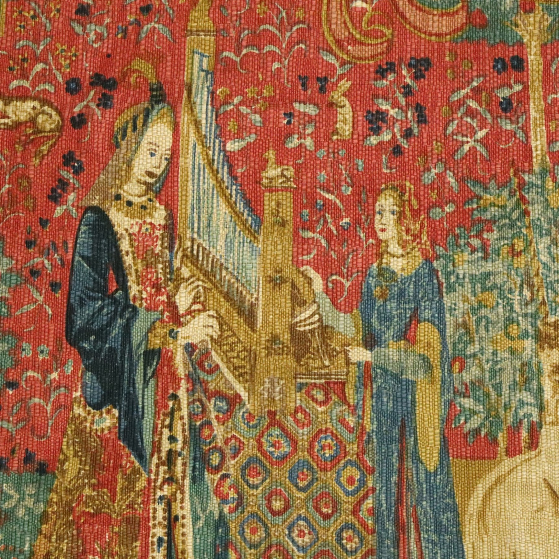 Neo-classical wall hanging, depicting women playing the harp surrounded by animals, on a red ground, with metal pole, L146cm