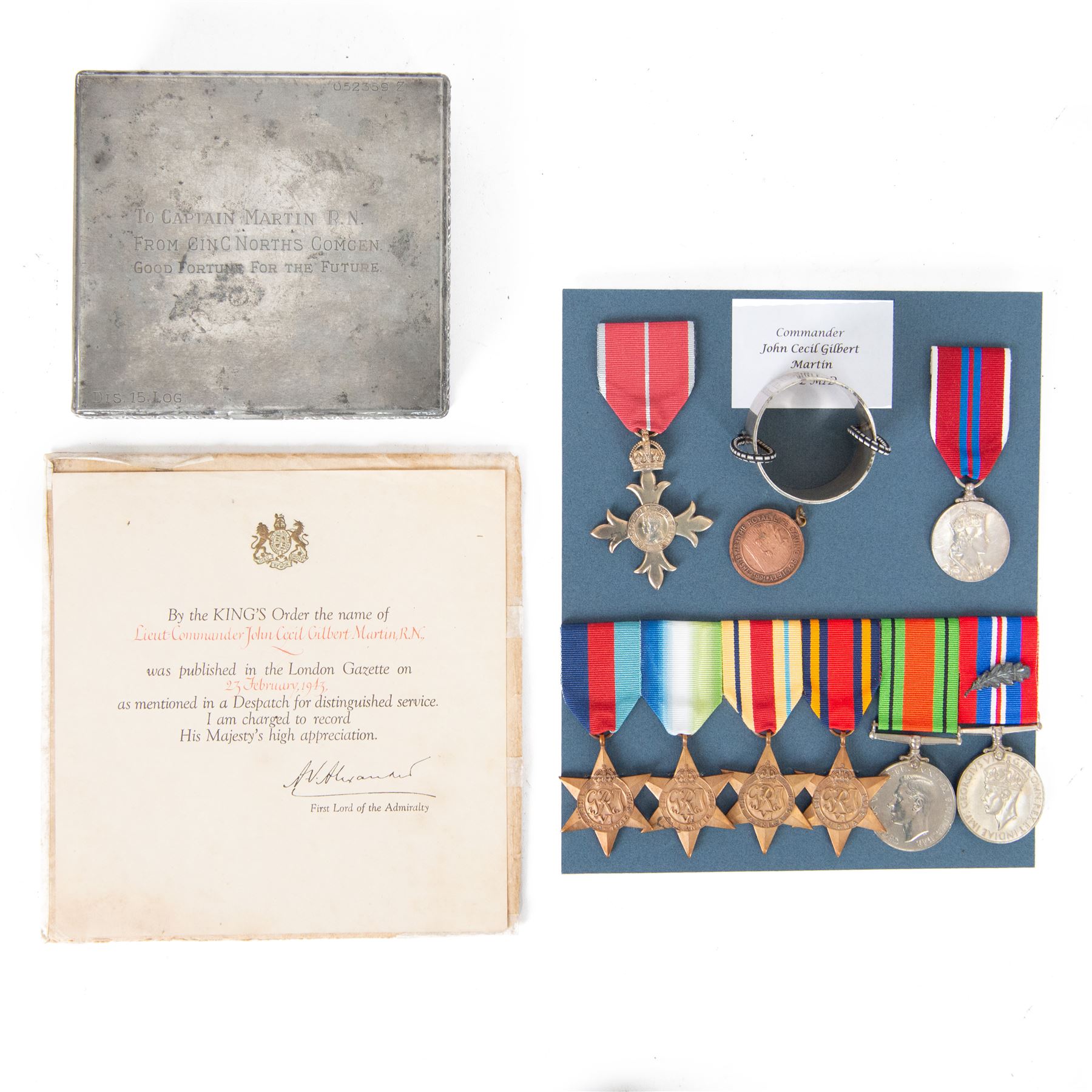 WWII Medal group awarded to Commander John Cecil Gilbert Martin, Royal Navy; OBE, 1939-1945 Star, Atlantic Star, Africa Star, Burma Star, War Medal, Defence Medal, Queen Elizabeth II Coronation medal and Royal Life Saving Society Medal, together with engraved silver napkin ring, hallmarked, engraved silver plated tin, OBE documentation and other ephemera relating to Commander John Cecil Gilbert Martin