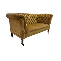 Early 20th century drop-arm chesterfield settee, upholstered in buttoned gold velvet fabric with sprung seat, raised on square tapering supports terminating in ceramic castors