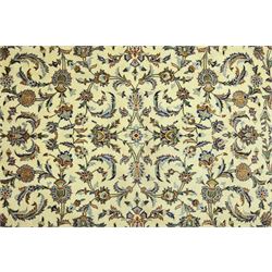 Central Persian Kashan carpet, ivory ground, field with an all-over design of scrolling palmettes and floral sprays in blue and terracotta within a beige ground and pale blue floral border