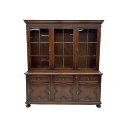 Waring and Gillow - oak bookcase on cupboard, projecting cornice over arcade frieze, guilloche upright decoration, the top section enclosed by three astragal glazed doors, the lower section enclosed by three geometric panelled doors with blind fretwork decoration, on turned feet