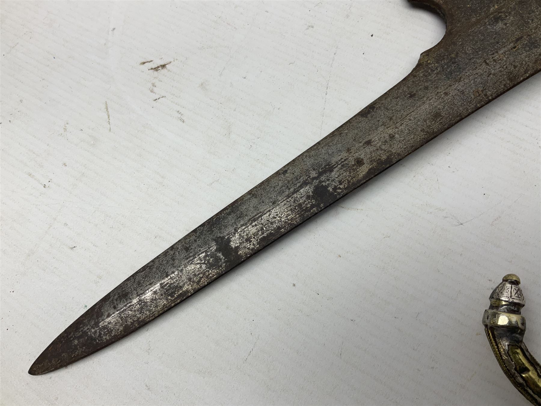 Moroccan jambiya dagger with 24.5cm plain curved blade stamped LONDON to the ricasso area, the hilt and scabbard overlaid with plain sheet brass to the back and ornate silver coloured metal to the front; waisted grip and arched pommel; two pyramid mounts to the scabbard L41cm overall; large billhook with curving blade and stacked leather washer grip; and a reproduction halberd blade (3)