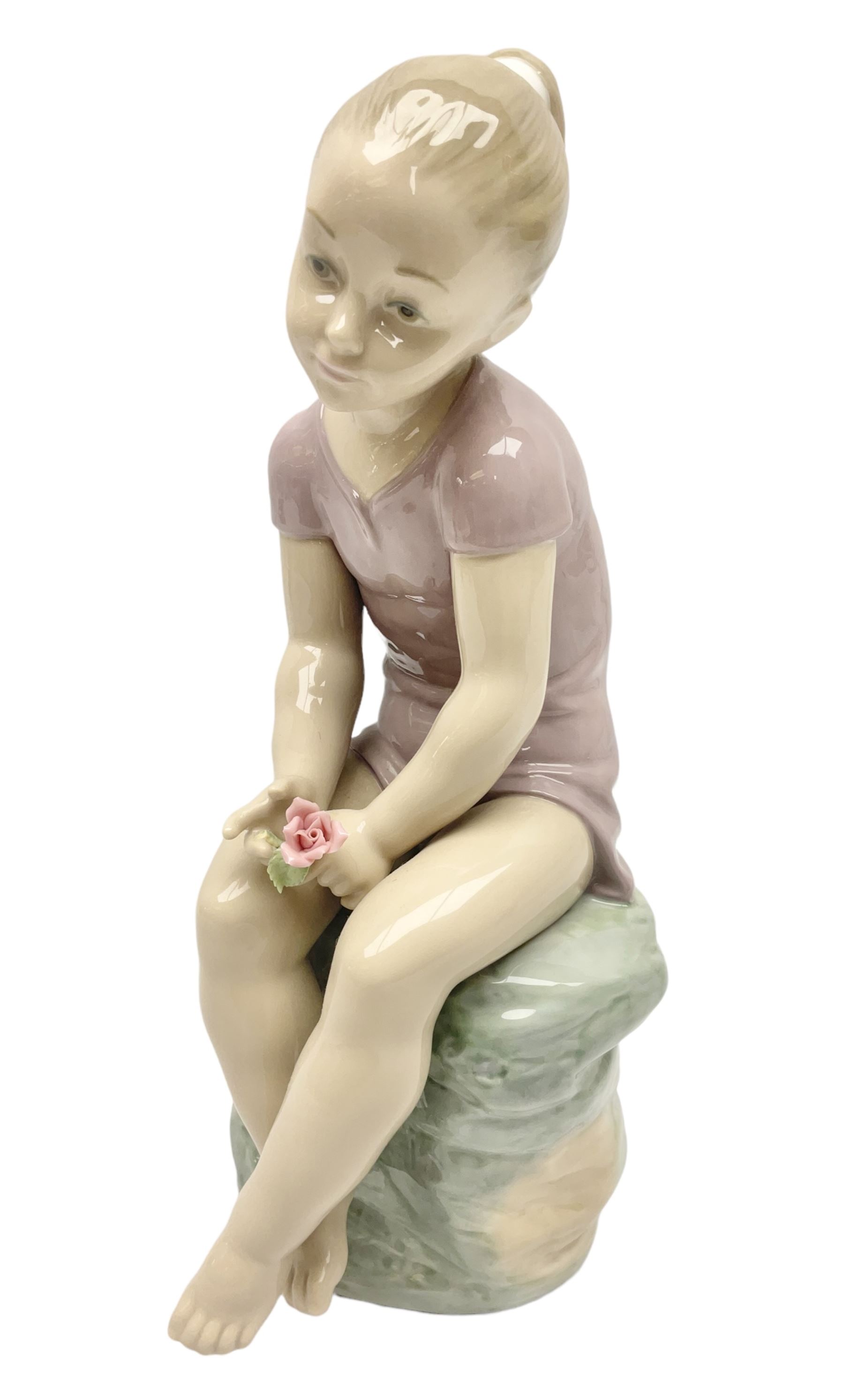 Large Nao figure modelled as a young girl seated upon a rock holding a rose, H30cm