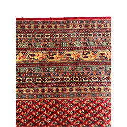 Persian Arak crimson ground carpet, the field decorated profusely with small repeating Boteh motifs, enclosed by multiple border bands decorated with repeating geometric and hook motifs