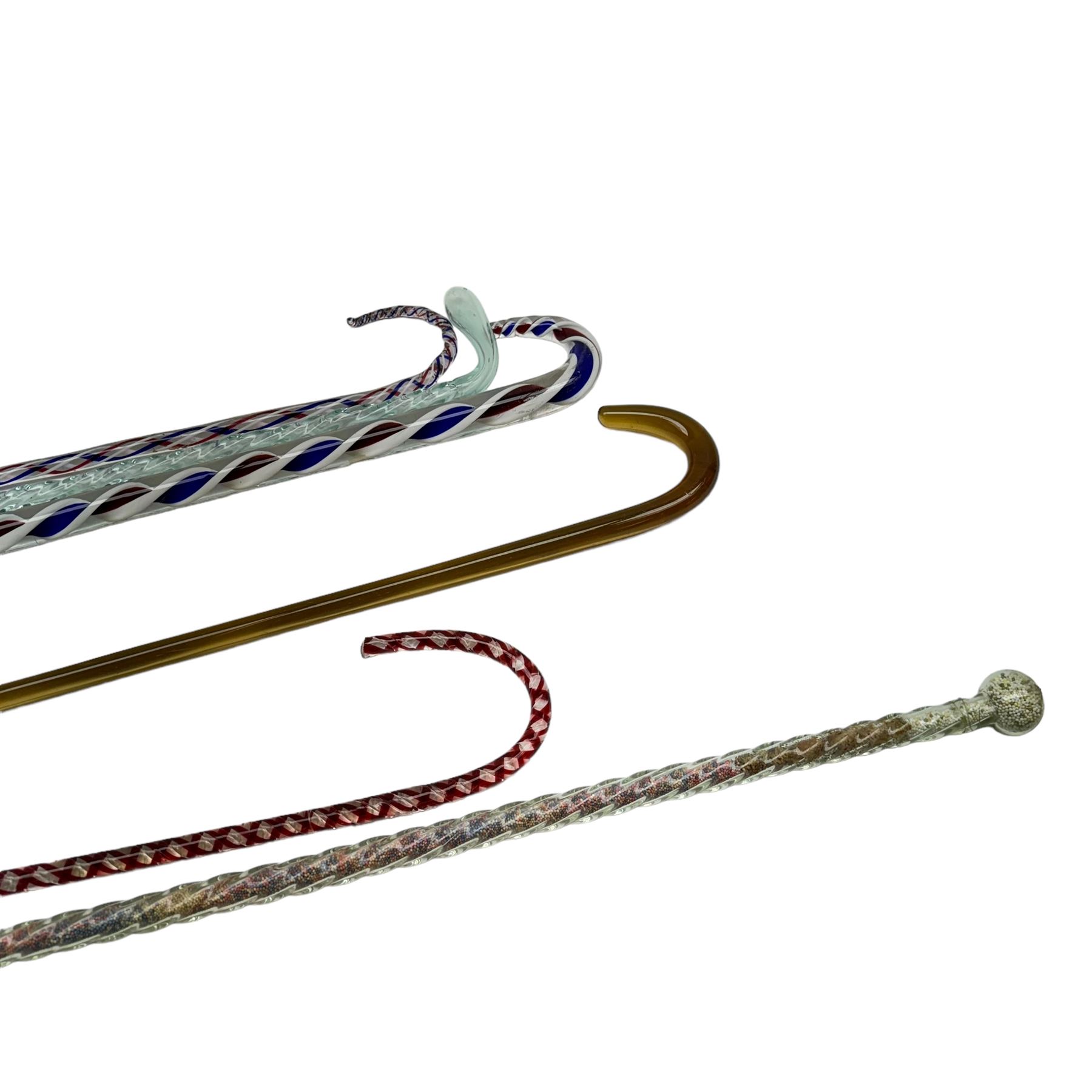 Six Victorian glass walking canes, to include three 'frigger' examples with colour twist designs, a 'hundreds and thousands' example with knop finial and filled with micro beads, possibly Nailsea, an opaque green twist example, and an amber glass example, longest L130cm