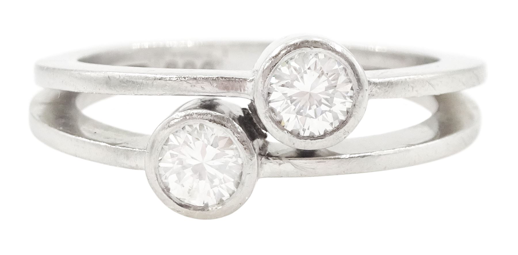 Platinum bezel set, two stone round brilliant cut diamond, crossover ring, London 1985, total diamond weight approx 0.50 carat