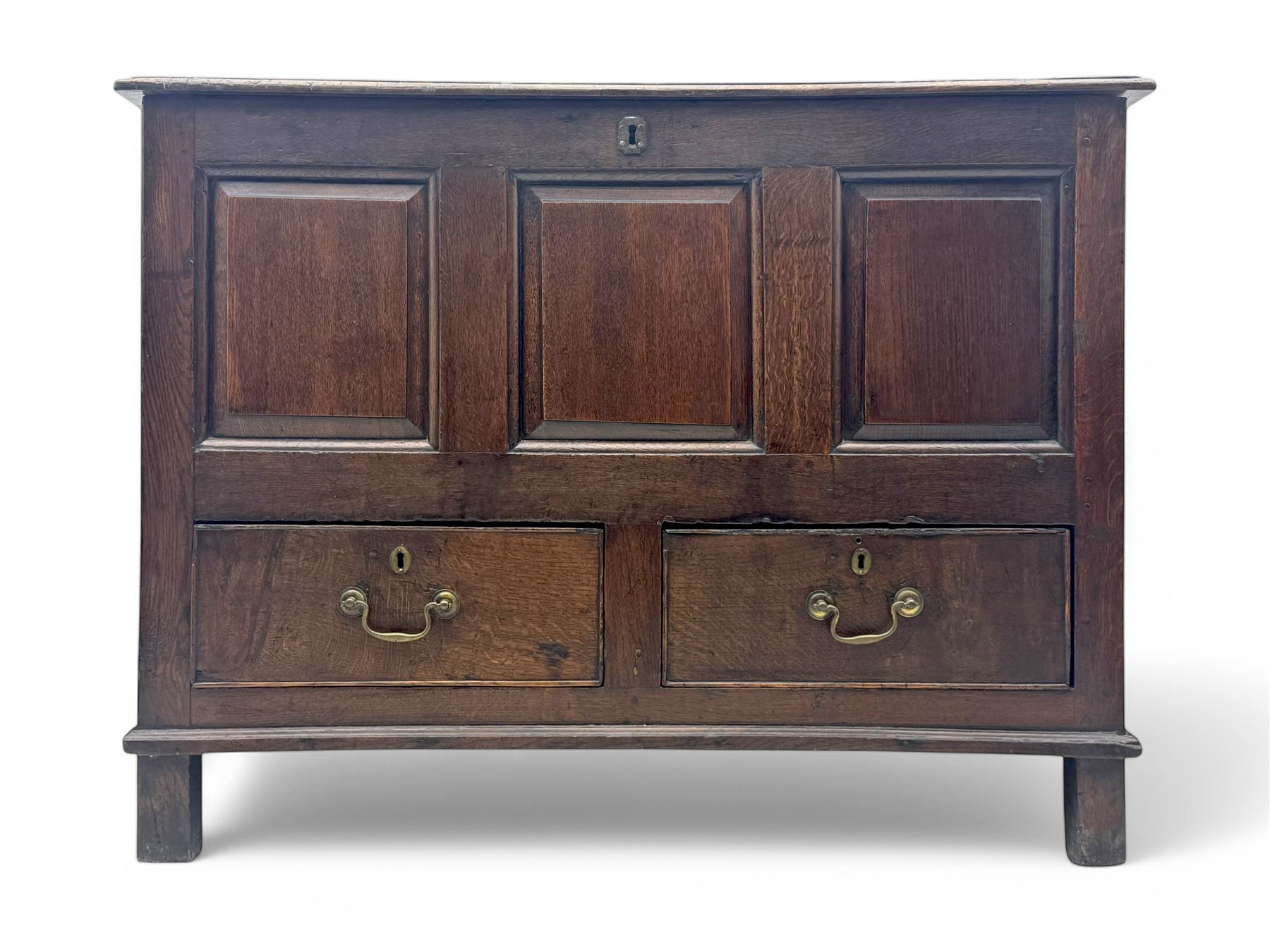 Early 18th century oak mule chest, hinged rectangular top above three recessed panels and two drawers, each fitted with brass drop handles, open interior fitted with candle box compartment, raised on square supports
