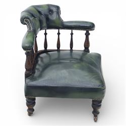 19th century green leather upholstered corner chair, with deep buttoned back and swept padded arms with close studded borders, raised on turned supports united by turned spindles, terminating in brass castors