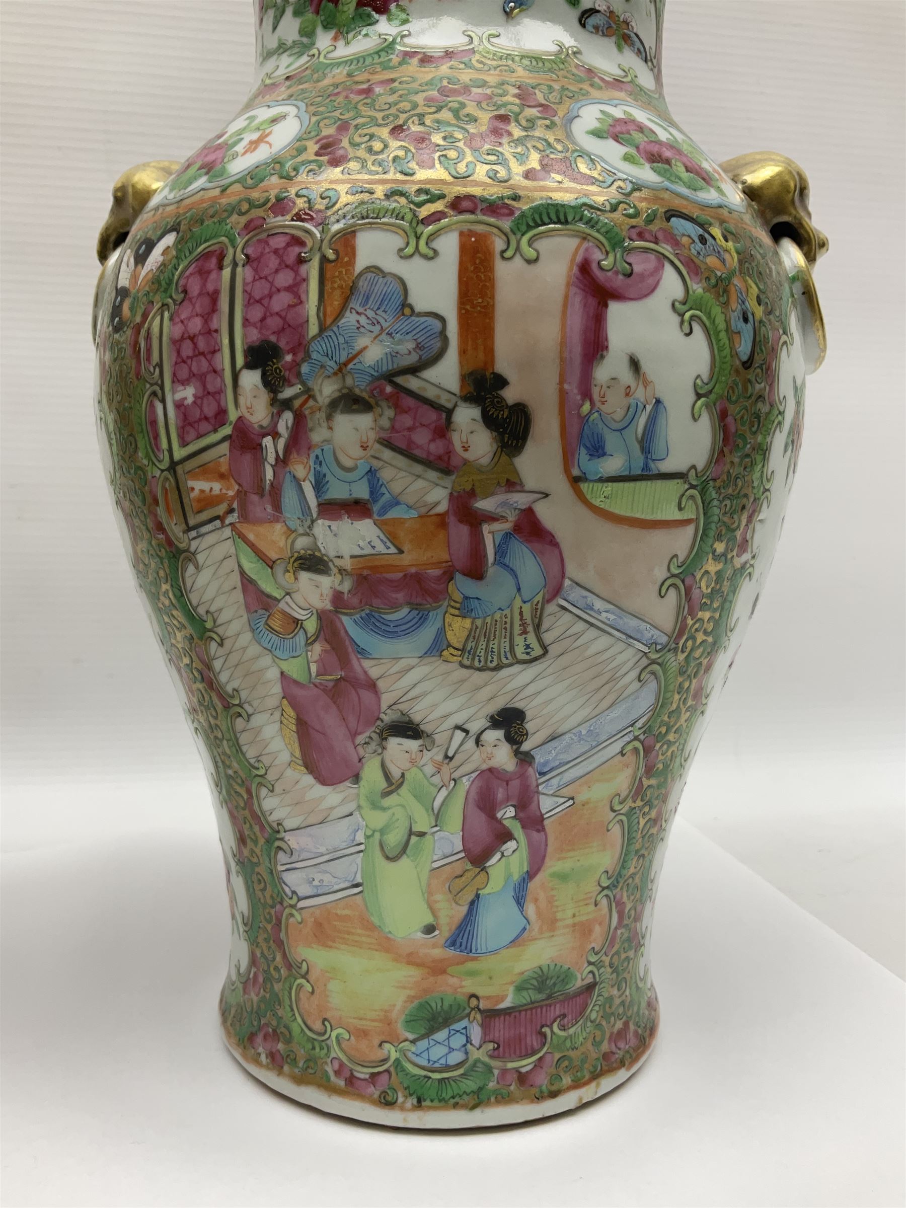 Pair of 19th century Chinese Famille Rose vases and covers, each of baluster form with twin gilt lion mask ring handles to shoulders, the flattened domed covers with gilt temple lion finials, each decorated with alternating reserves of bijin and attendants, and birds and butterflies amongst blossoming peonies, against a gilt ground profusely decorated with stylised scrolls, H32.5cm