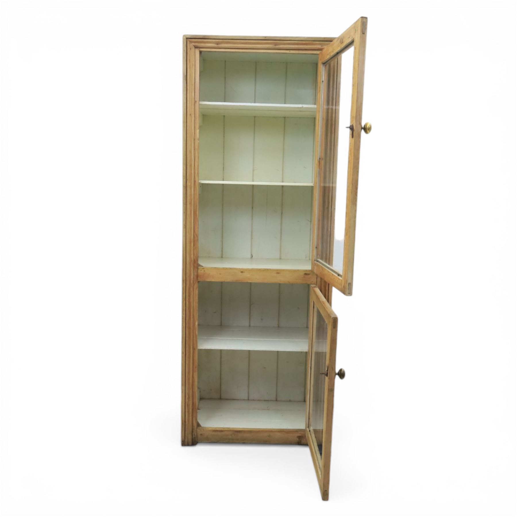 Early 20th century waxed pine kitchen cupboard, rectangular form with moulded top, enclosed by two glazed doors revealing painted interior with shelves, boarded sides and back, fitted with brass knob handles