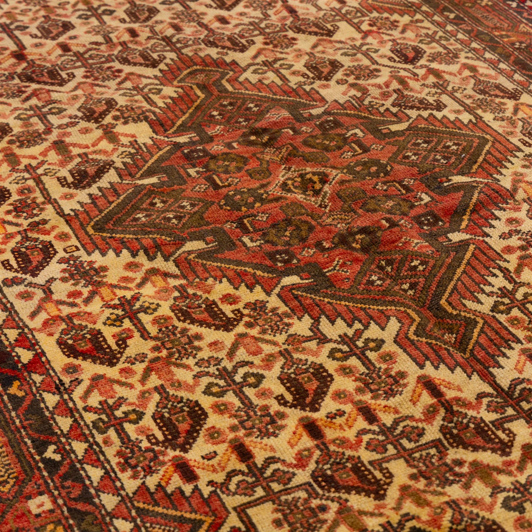 North West Persian Malayer hand-knotted rug, ivory field with central stepped lozenge medallion with angular pendants, surrounded by rows of stylized boteh and geometric floral devices within multiple geometric and stylized vine borders, with fringe ends