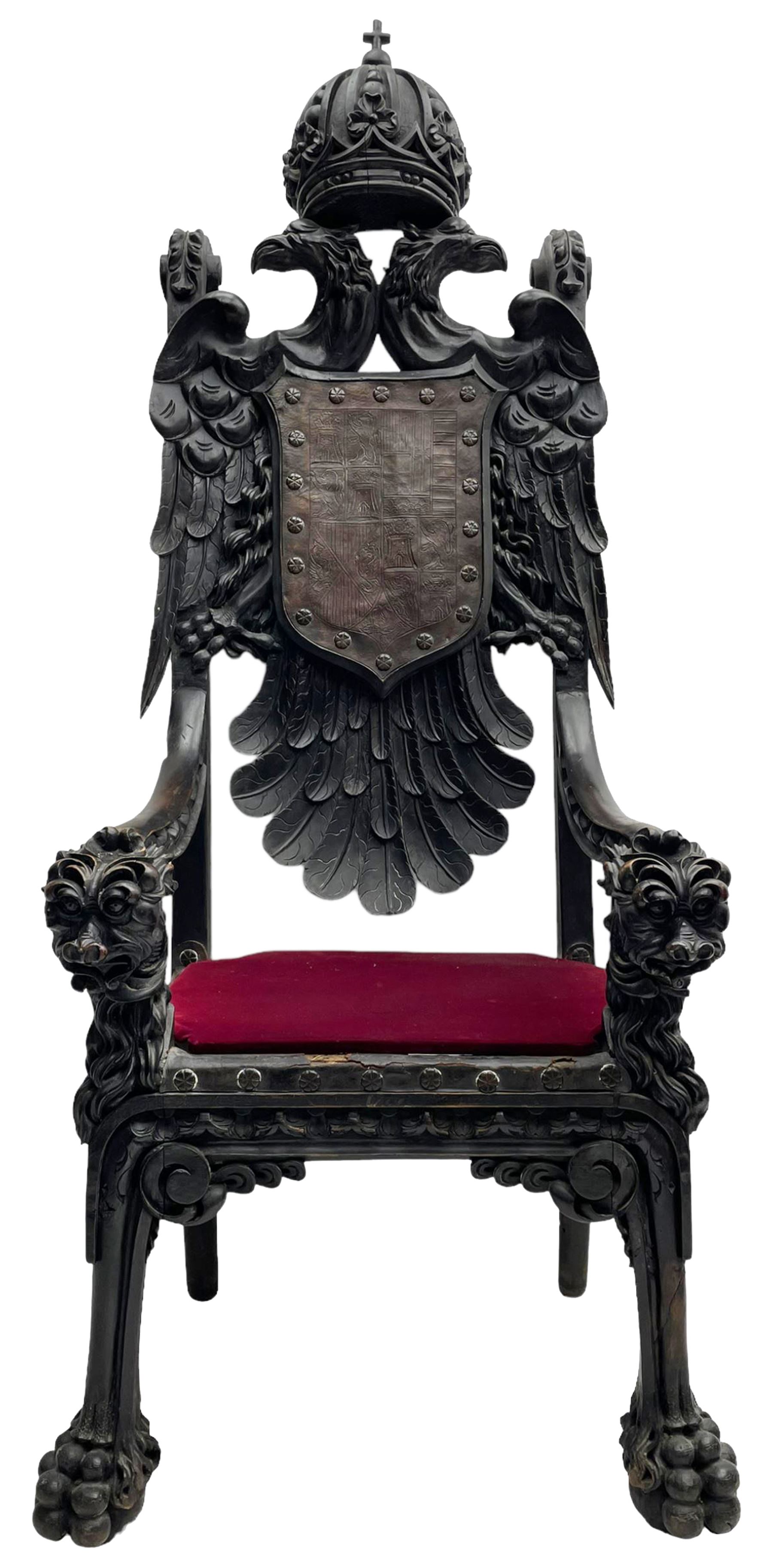 Grand mid-to-late 19th century heavily carved beech framed throne chair, the crown pediment carved with flower heads and cross finial, scroll and acanthus carved upright supports with twin perching griffin back enclosing etched leather work heraldic shield with castle and lion motifs over splayed feathers, flower head carved down sweeping arms with grotesque carved terminals, the seat rails carved with further flower heads on moulded supports with oversized ball and claw carved feet

Provenance: A very similar chair was used in the filming of Stanley Kubrick's 'Eyes Wide Shut' (1999)
