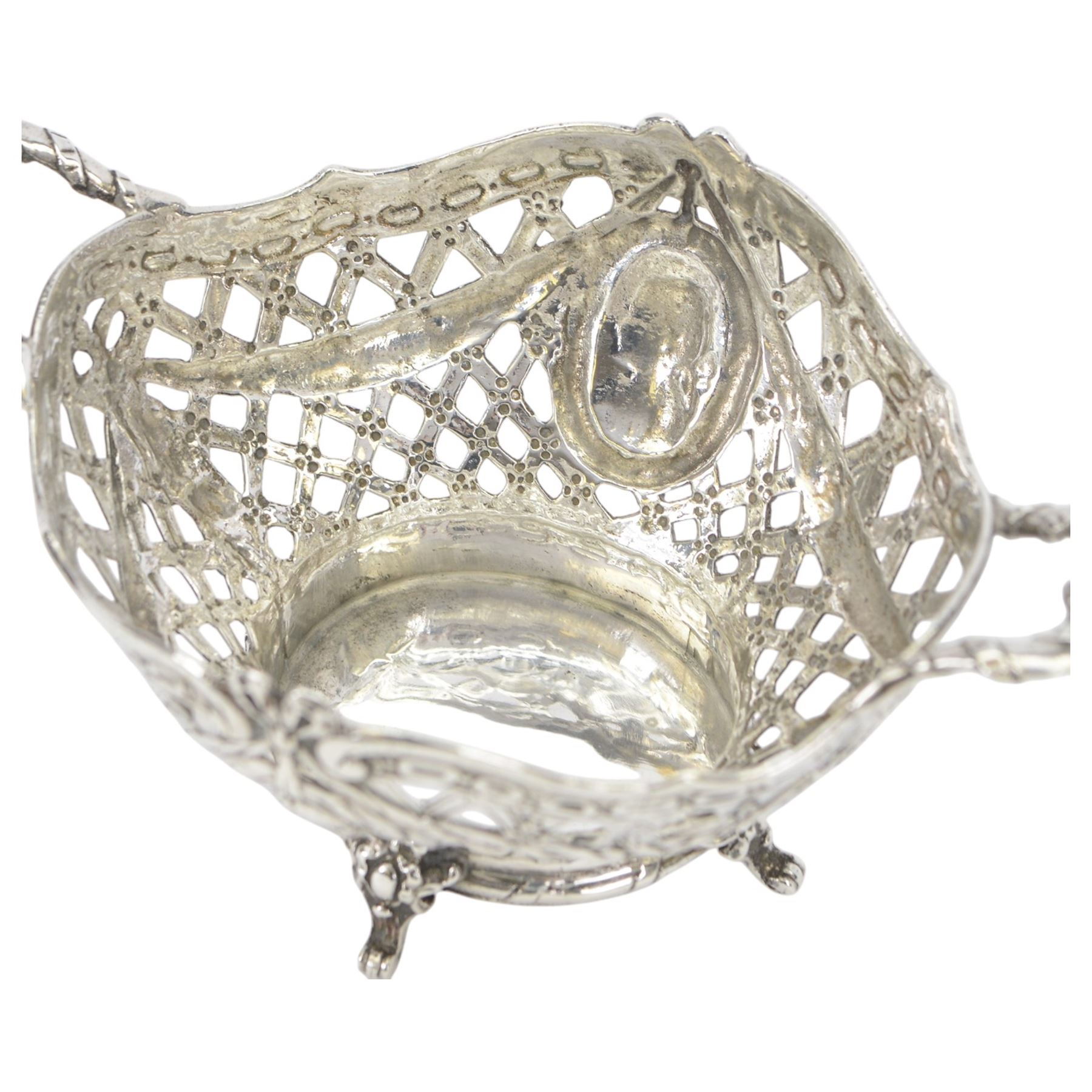Late 19th/early 20th century German Hanau silver basket, modelled in George II style, of shaped openwork lattice form with twin handles, the body decorated with two portrait roundels and husk and ribbon swags, upon four scroll feet, with unattributed pseudo Hanau marks, and hallmarked John George Piddington, London import 1901, including handles H7cm W15cm
