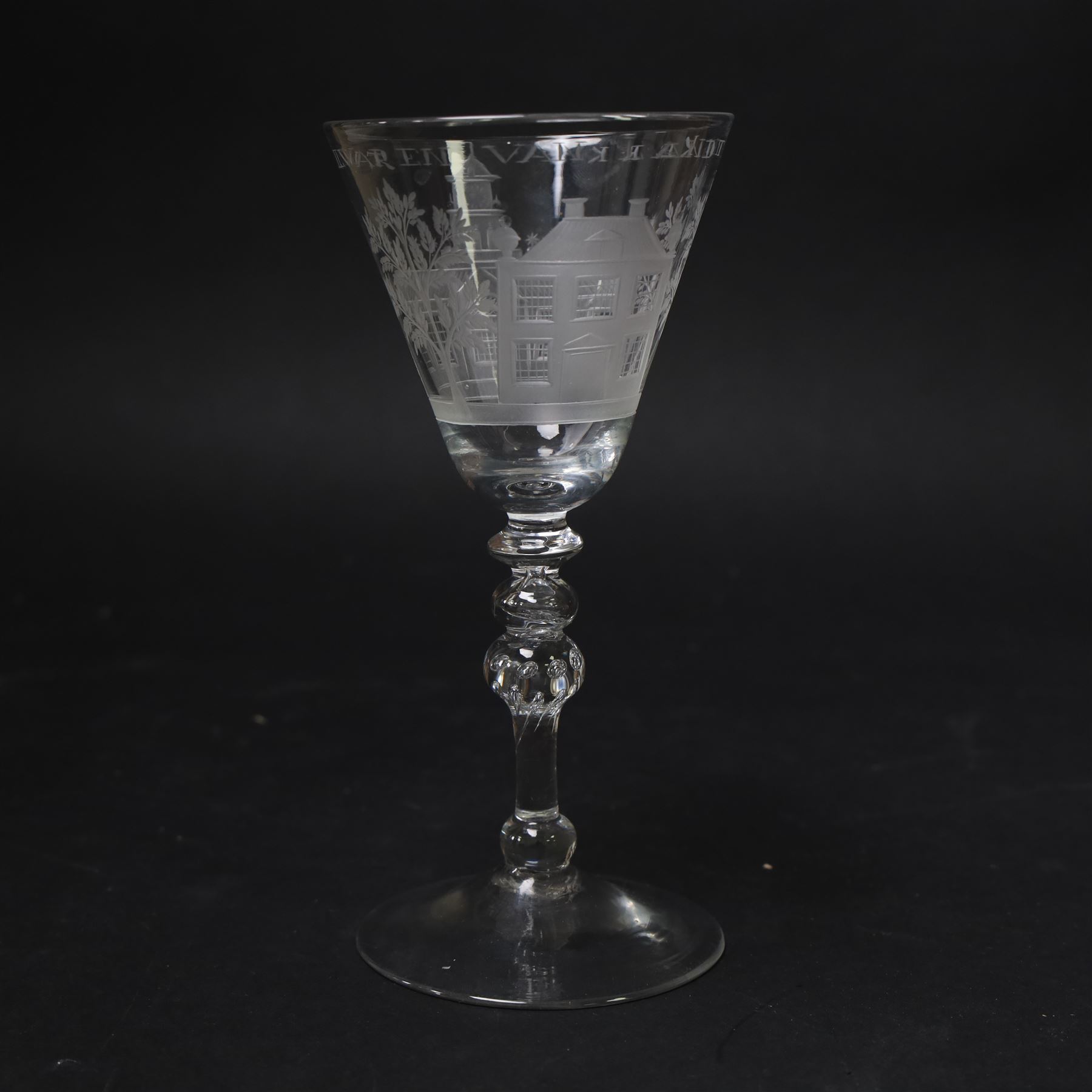 Dutch engraved Newcastle light baluster glass, circa 1760, the funnel bowl engraved with a two storey country house and church flanked by trees, beneath the inscription ‘T WELVAREN VAN LANDT ENKERK’ (The prosperity of the Country and Church), upon a multi knopped stem with beaded knop and basal knop, over conical foot, H18cm



