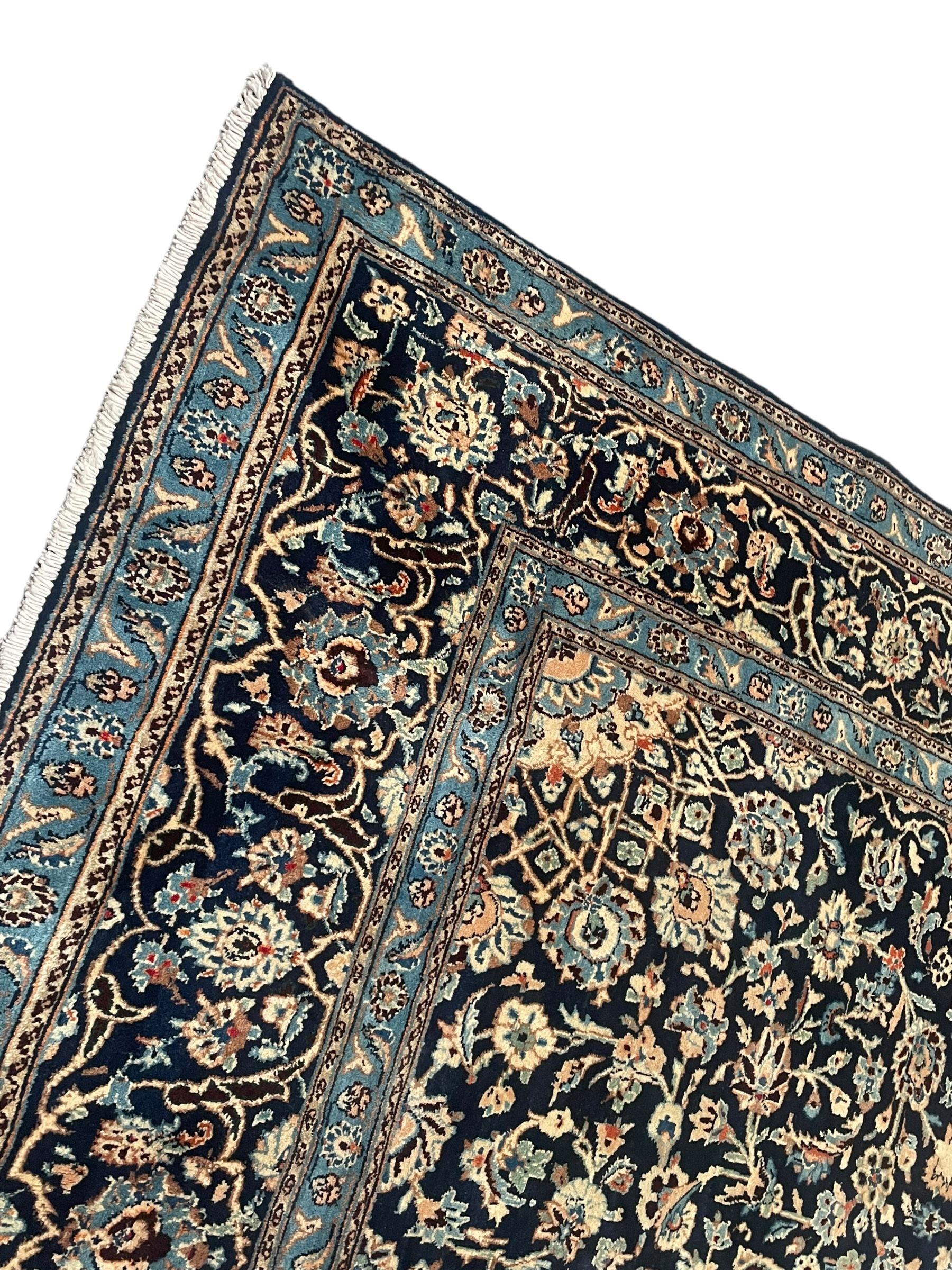Persian Kashan indigo ground rug, the rosette medallion decorated with projecting palmettes, on a field of swirling leafy branches and decorated with further palmettes, the scrolling border with repeating stylised plant motifs, within floral pattern guard stripes