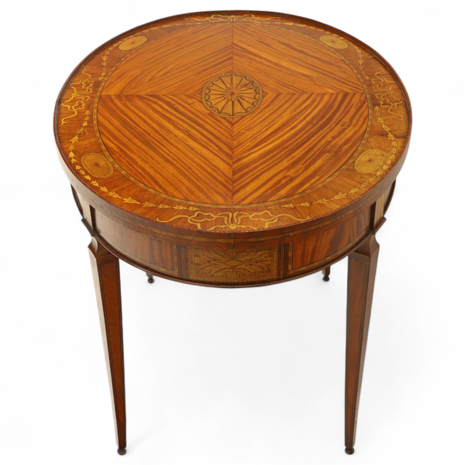 Aldam Heaton & Co (fl.1878-97) - late 19th century Sheraton revival style satinwood inlaid oval centre table, raised inlaid edge, centre with finely executed large central  inlaid medallion, surrounded by ribbon tied swags interspaced with medallions, frieze with rectangular symmetrical panels of foliate sprays of acanthus leaves, raised on four square section tapering legs with cavetti shaped shoulders with stringing on brass bulb feet, underside with bone plaque signed Aldam Heaton & Co, Baker St, London