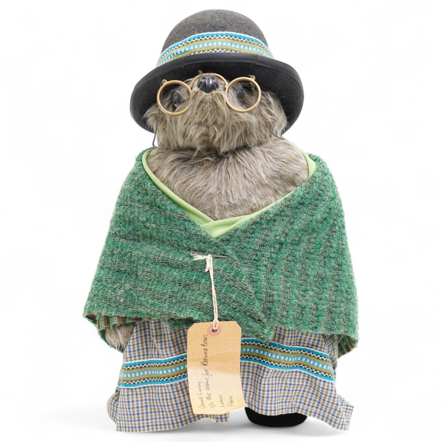 Gabrielle Designs Paddington Bear 'Aunt Lucy', 1978, dressed in green shawl, with hat and spectacles, tartan dress and luggage tag from the Peruvian Rugby FC Reserves Supporters Club, H50cm
