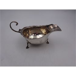 Two 1920s silver sauceboats, the first example of typical form, with flying scroll handle and engraved initial, upon three hoof feet, hallmarked Asprey & Co Ltd, Birmingham 1929, the second example smaller with shaped rim, upon three pad feet, hallmarked William Neale & Son Ltd, Birmingham 1928, including handle tallest H7.6cm