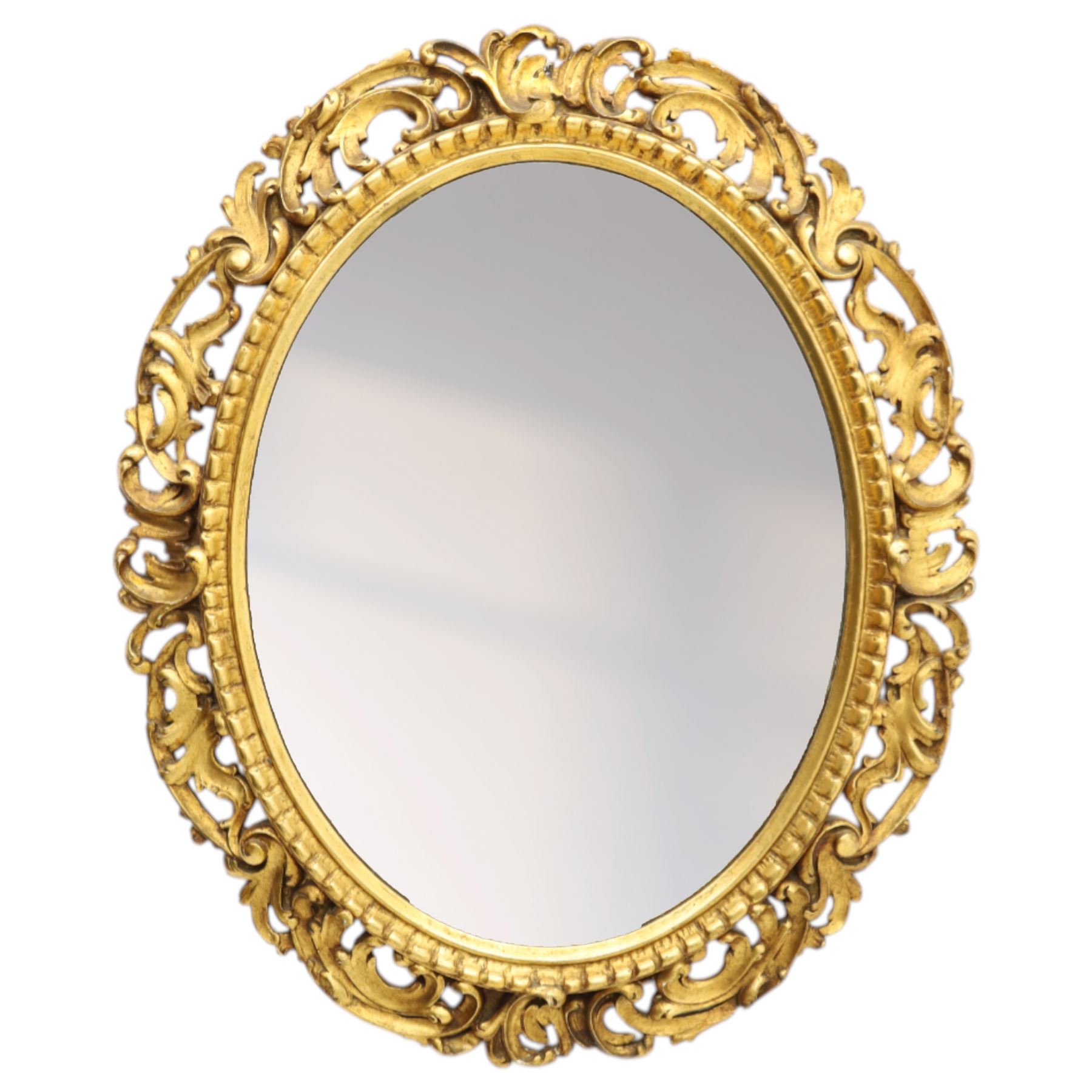 Late 19th century giltwood oval wall mirror, the bevelled plate within a gadroon moulded inner slip, surrounded by pierced scrolling foliate and acanthus carved frame, richly gilded with worn patina indicative of age and use