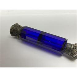 Late Victorian silver mounted ruby glass cylindrical scent bottle, with interior glass stopper, Birmingham 1900, makers mark worn, H8cm, together with a Victorian double ended cut blue glass perfume bottle mounted with white metal screw and flip caps decorated with foliate repousse detailing, H13.5cm