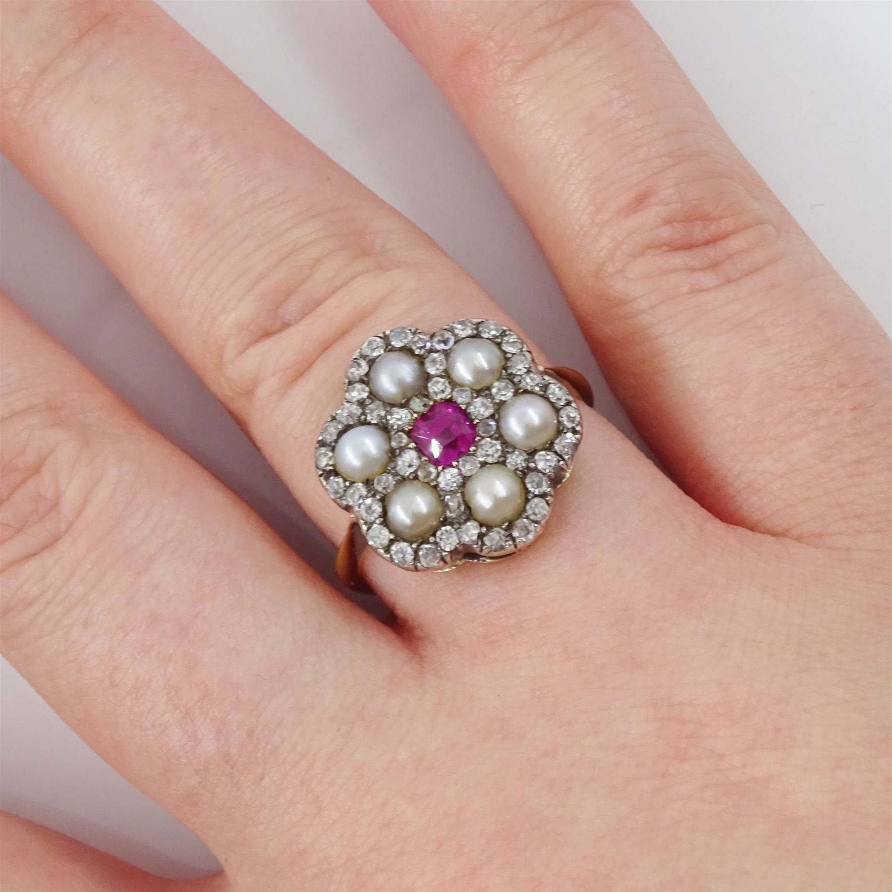 Early 20th century 18ct gold and silver ruby, diamond and pearl flower head cluster ring, single octagonal cut ruby of approx 0.30 carat, with old cut and rose cut diamond and split pearl surround