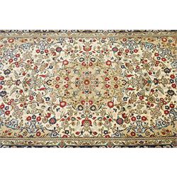 Central Persian Kashan hand-knotted carpet, ivory ground with a central floral medallion with an all-over design of scrolling vinery, palmettes, and flowering sprays i tones of madder red, cobalt, navy blue and sage green, with conforming spandrels, main border of deep indigo ground with repeating palmettes and stylized floral heads, flanked by narrow guard stripes, with cotton fringe ends, with cotton fringe ends 