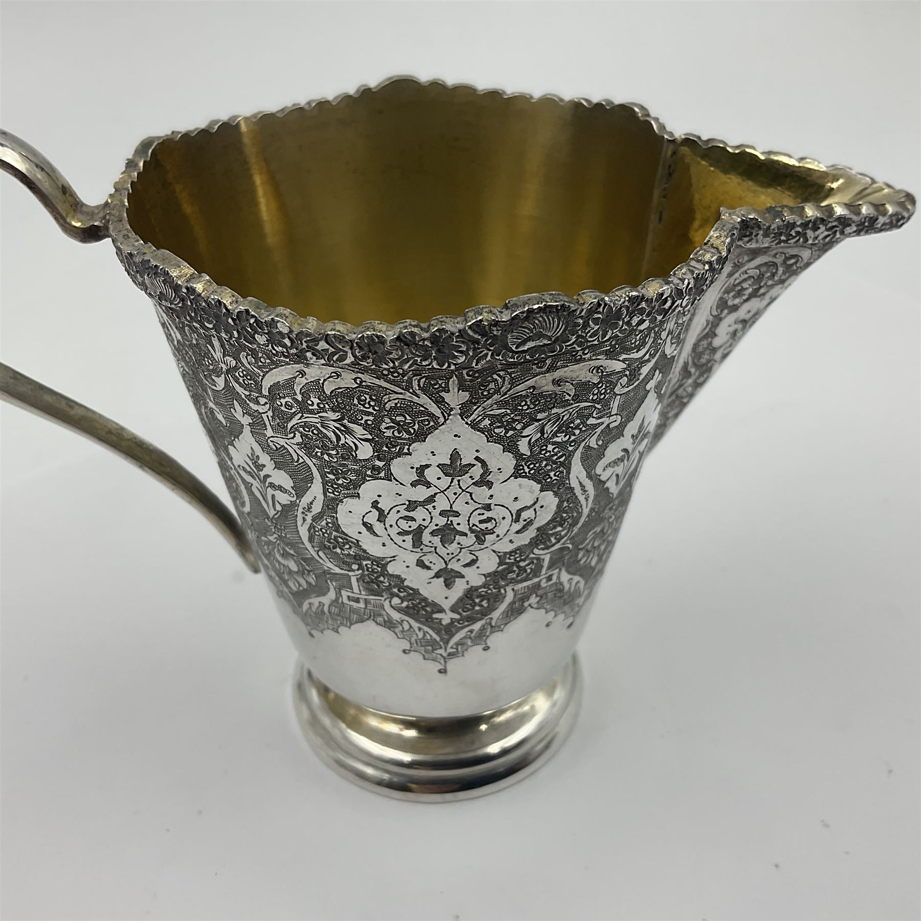 Early/mid 20th century Persian silver tea service, comprising circular serving tray, teapot, twin handled sucrier and cover, milk jug, five tea glasses with six silver holders, six tea spoons, and pair of sugar tongs, each profusely chased with foliate arabesque decoration, each bearing marks including 84 for 840 fineness, tray D40cm, teapot H16cm