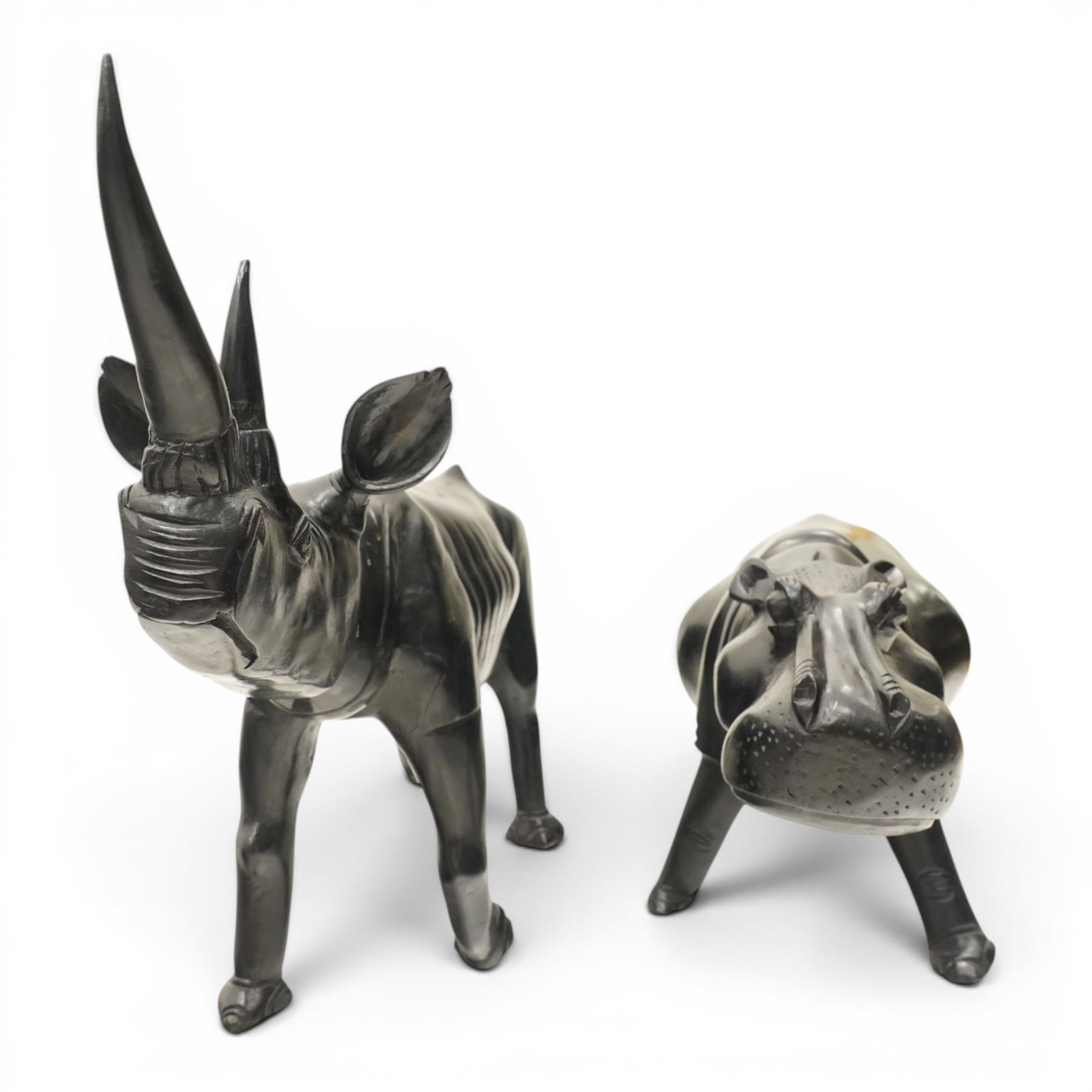 African carved hardwood ebonised figures of a rhinoceros and hippopotamus, each with stylised incised detail and polished dark finish, largest H 61cm, W 91cm)